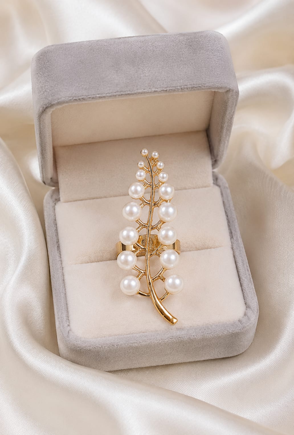 Gold-plated leaf statement ring with pearl-like beads displayed in jewelry box