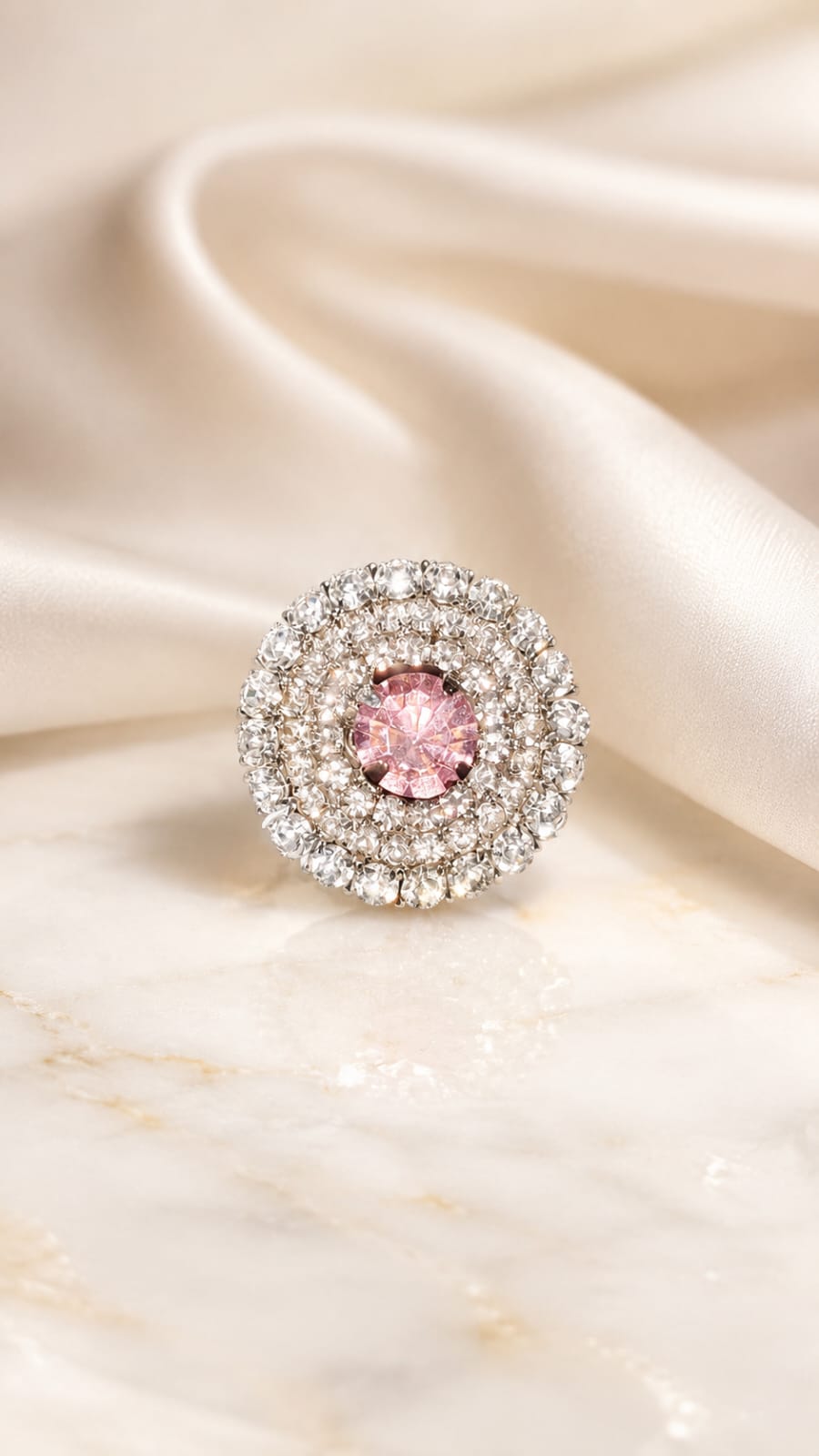 Silver-tone round halo ring with blush-pink center stone and surrounding clear crystals
