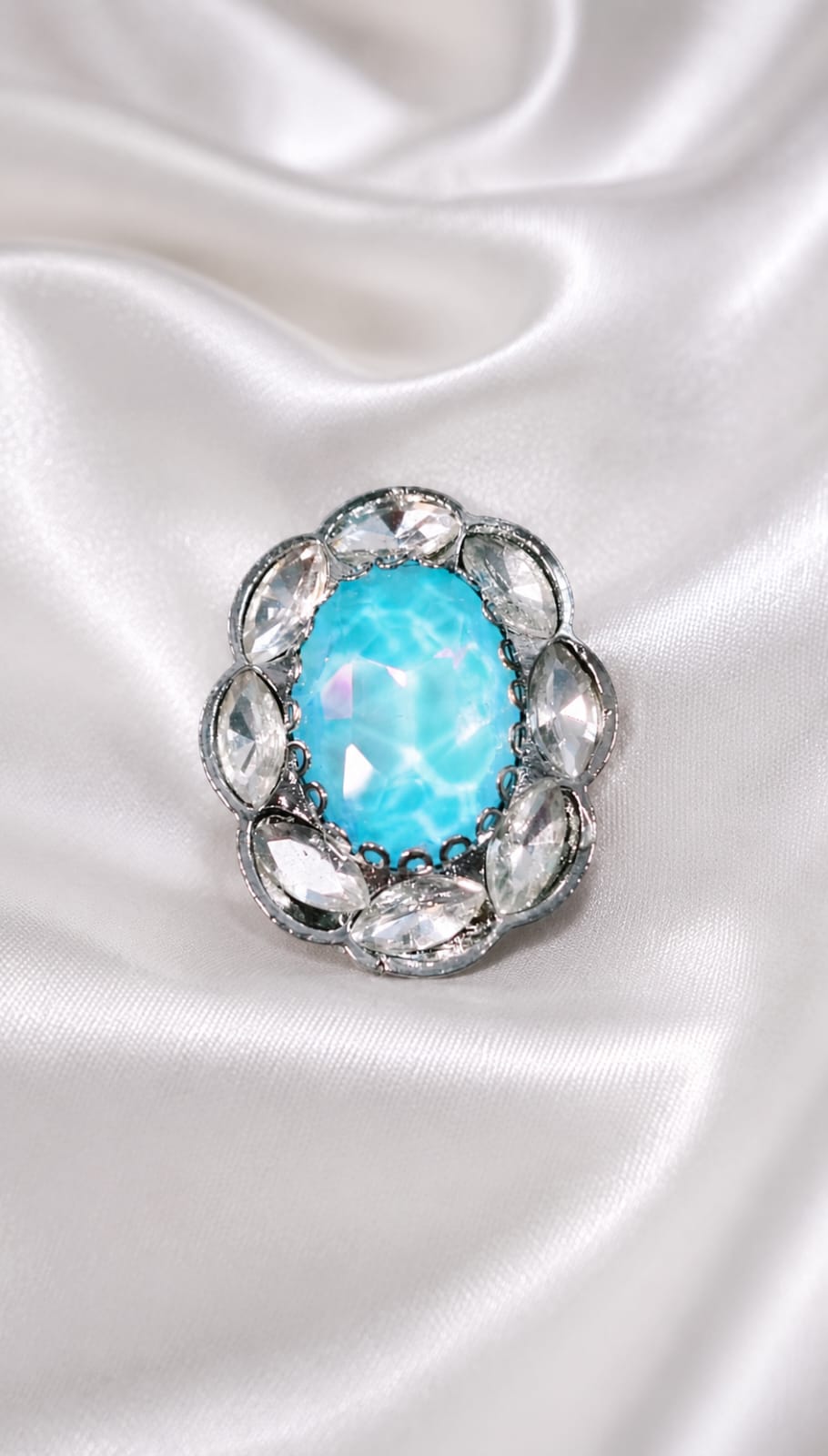Gunmetal oval aqua-blue halo ring with teardrop crystal settings around the center