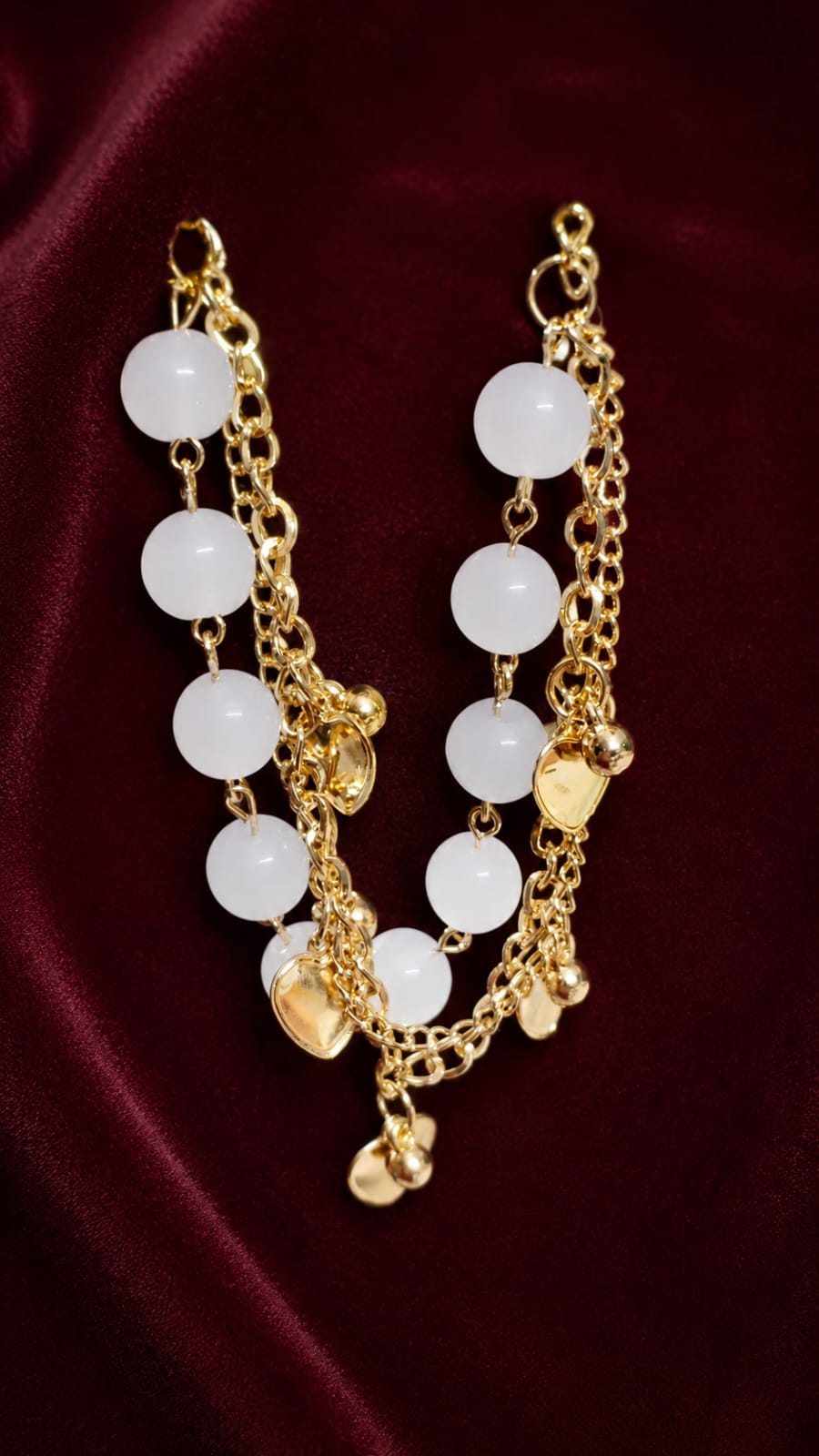 Gold-plated charm bracelet with white round beads and dangling gold charm links