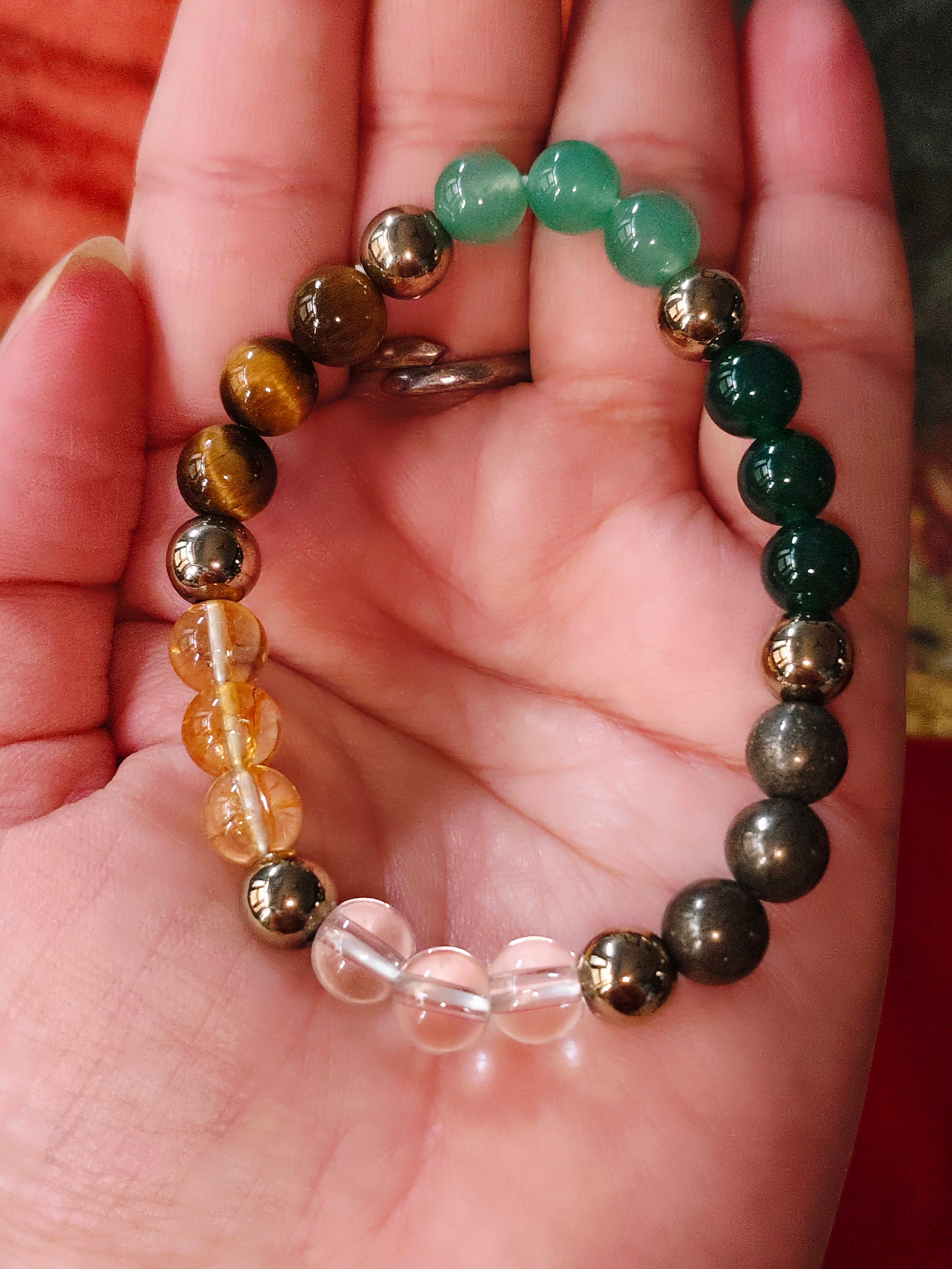 Crystal bracelet on palm: green, tiger-eye brown and clear quartz-style beads
