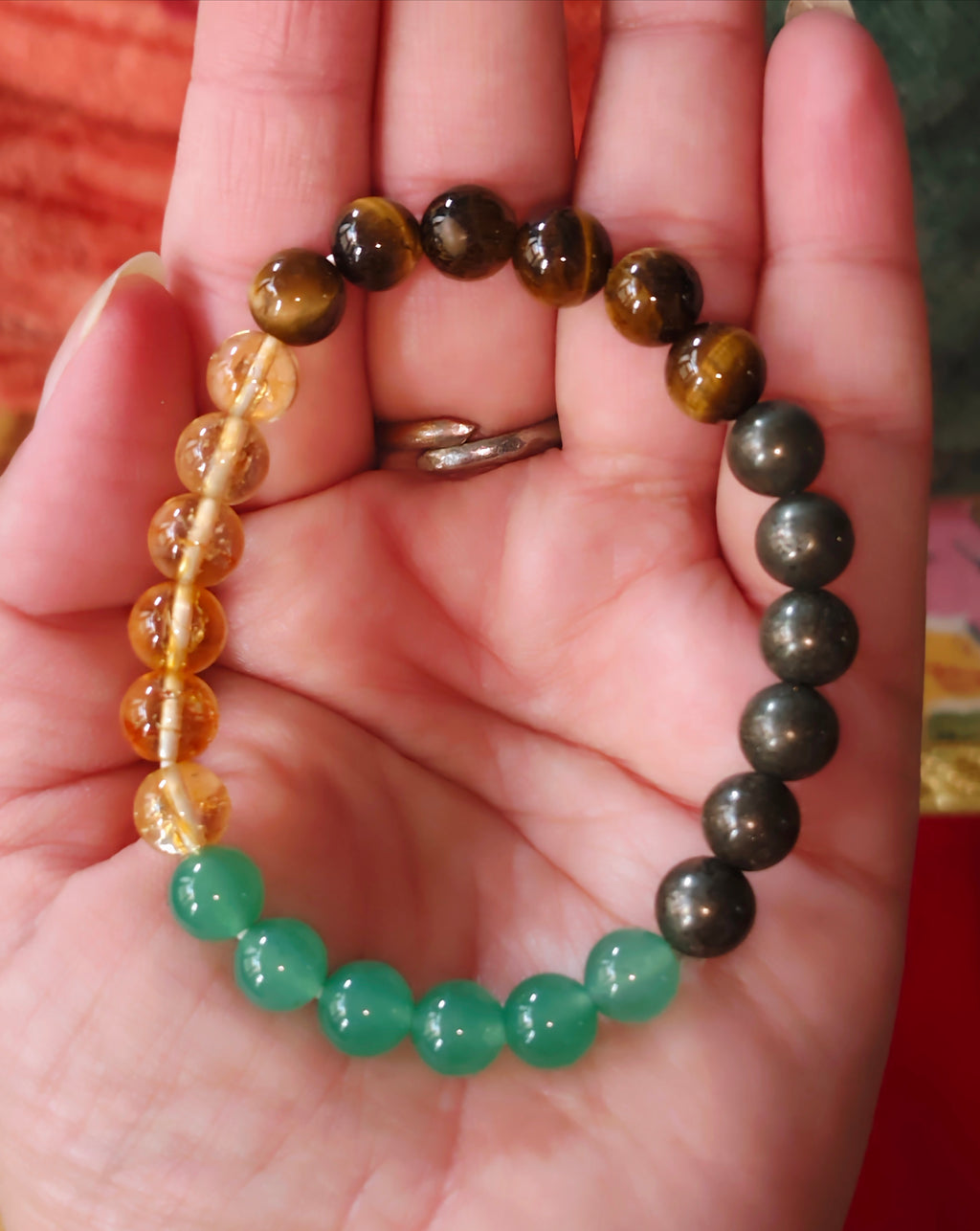 Crystal bracelet in hand, dark and green beads with gold-toned clasp