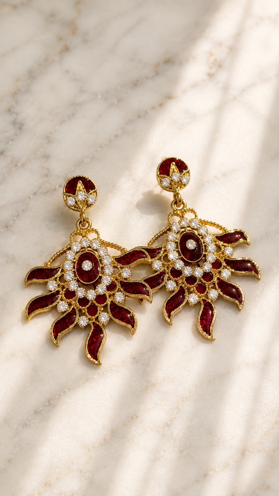 Gold-tone drop earrings with red enamel flower design, round dark centers, white rhinestone halos.