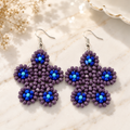 Purple beaded floral drop earrings with blue bead centers and silver hooks