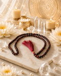 Red tiger eye crystal mala with dark brown beads and red tassel, on display