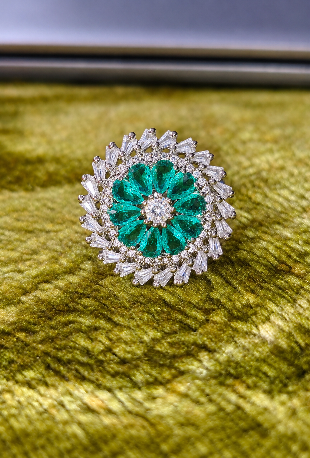 Silver-tone ring with emerald-green round center and clear stone halo