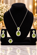 Silver necklace set with oval green center stone, matching earrings on dark display