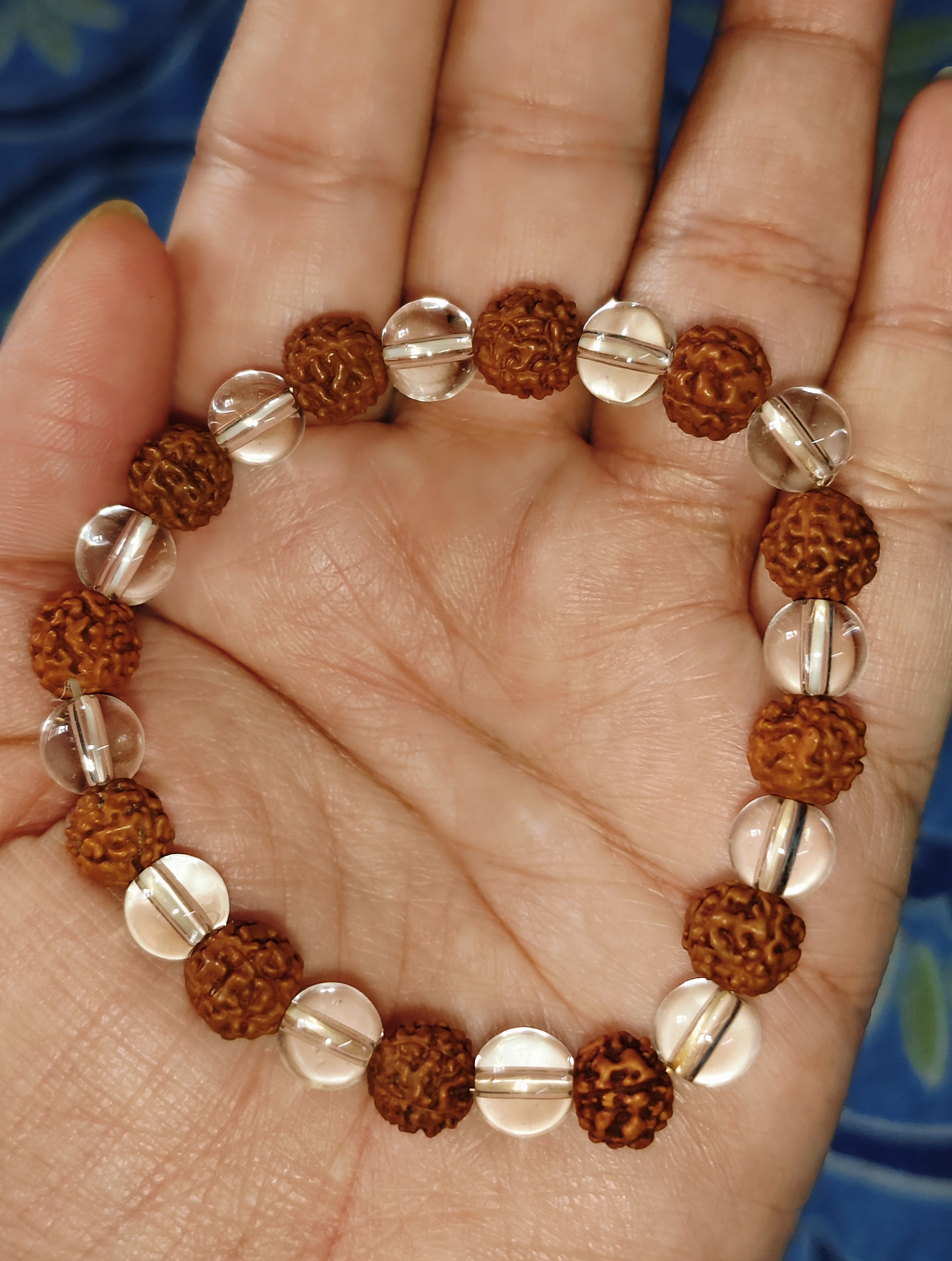 Rudraksha-style brown beads with clear quartz accents bracelet shown in hand