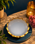 White selenite charging bowl with gold rim on dark blue dish